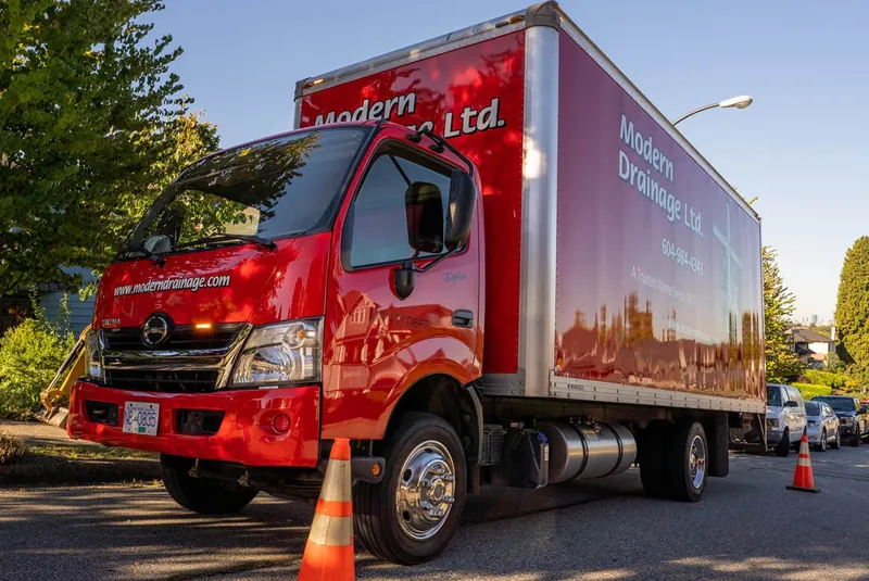 A branded Modern Drainage box truck parked at a job site.